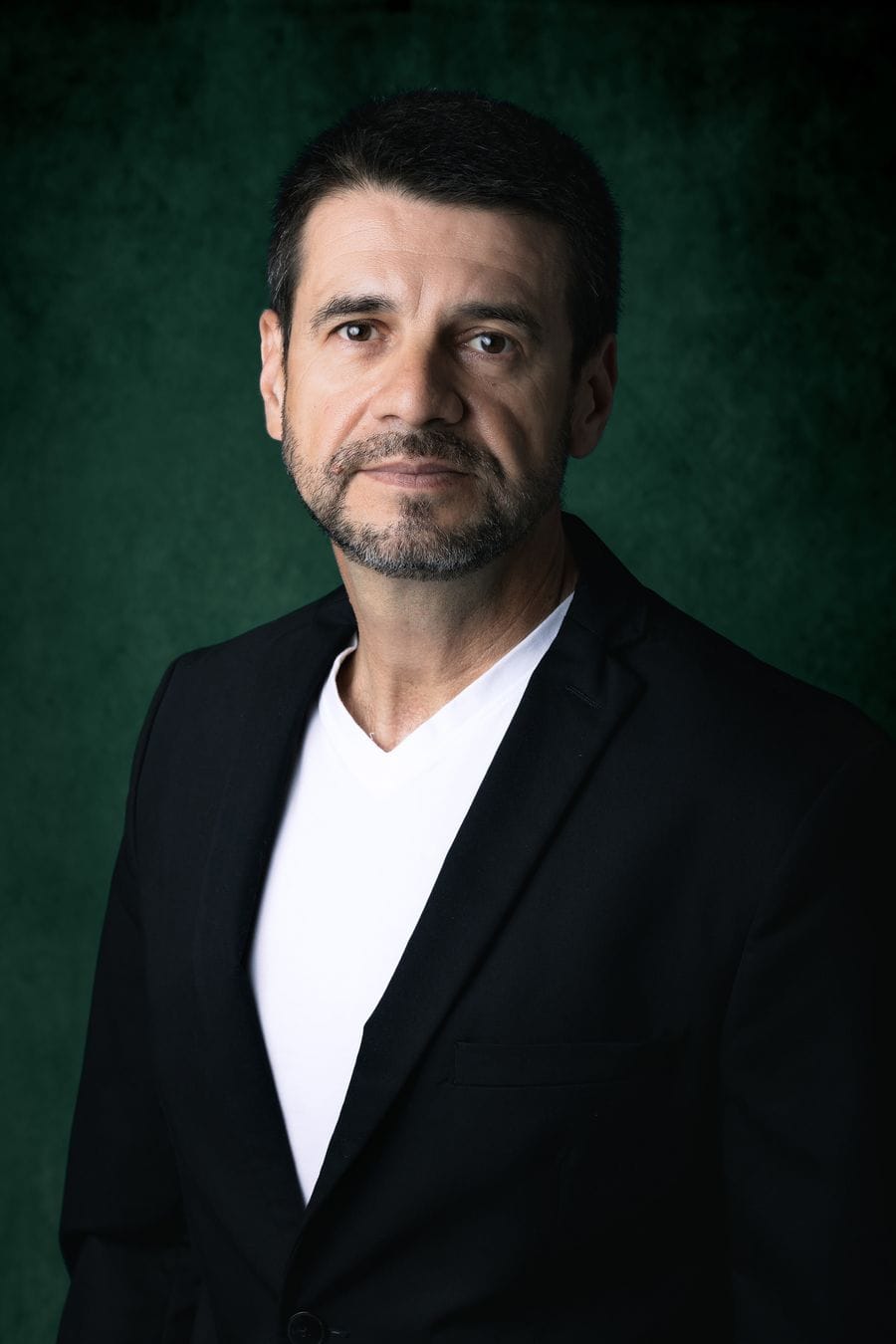 Emerson Pereira, gestor de tráfego pago, de blazer preto sobre fundo verde