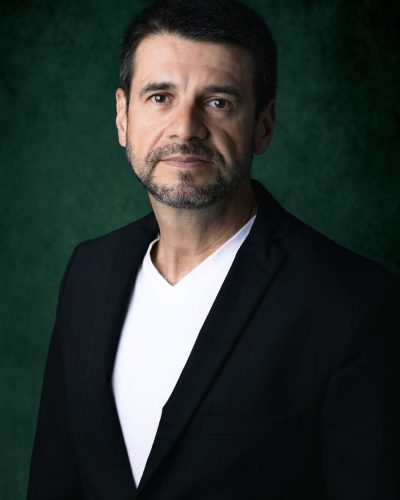 Emerson Pereira, gestor de tráfego pago, de blazer preto sobre fundo verde